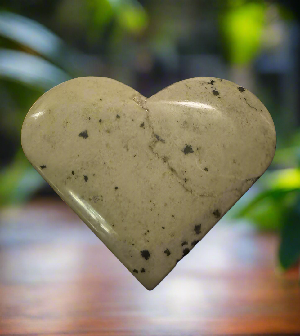 Heart-shaped, pale stone with dark speckles.