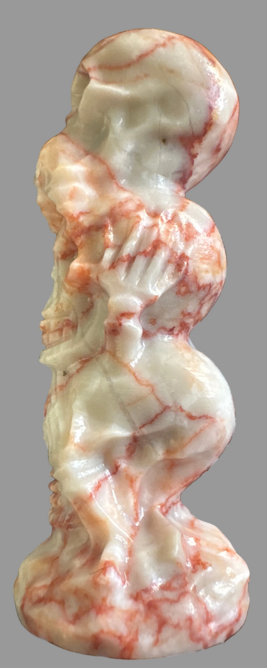 Stack of four carved skull-shaped stones with reddish-orange veining.