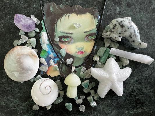 Assorted crystals, shells, and a cartoon face on a green marble surface.