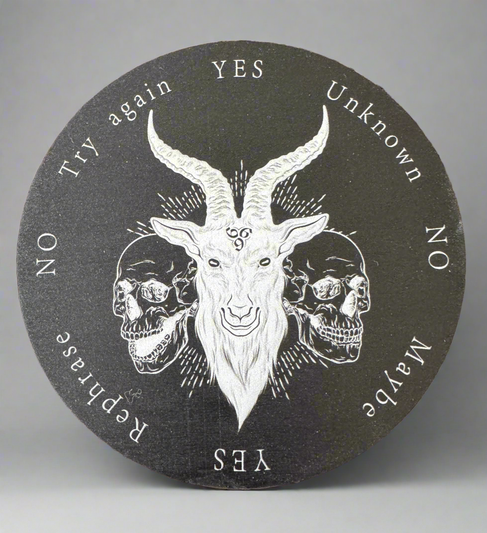Round, dark-gray spirit board with a central goat head illustration flanked by two skulls and text options of "yes," "no," "maybe," "unknown," "rephrase," and "try again."