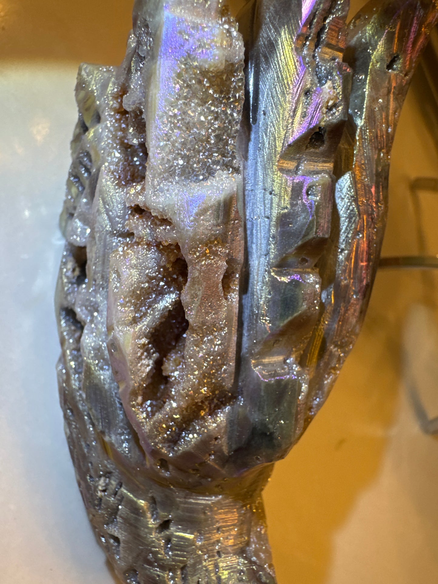 Iridescent druzy quartz sculpture with carved details.