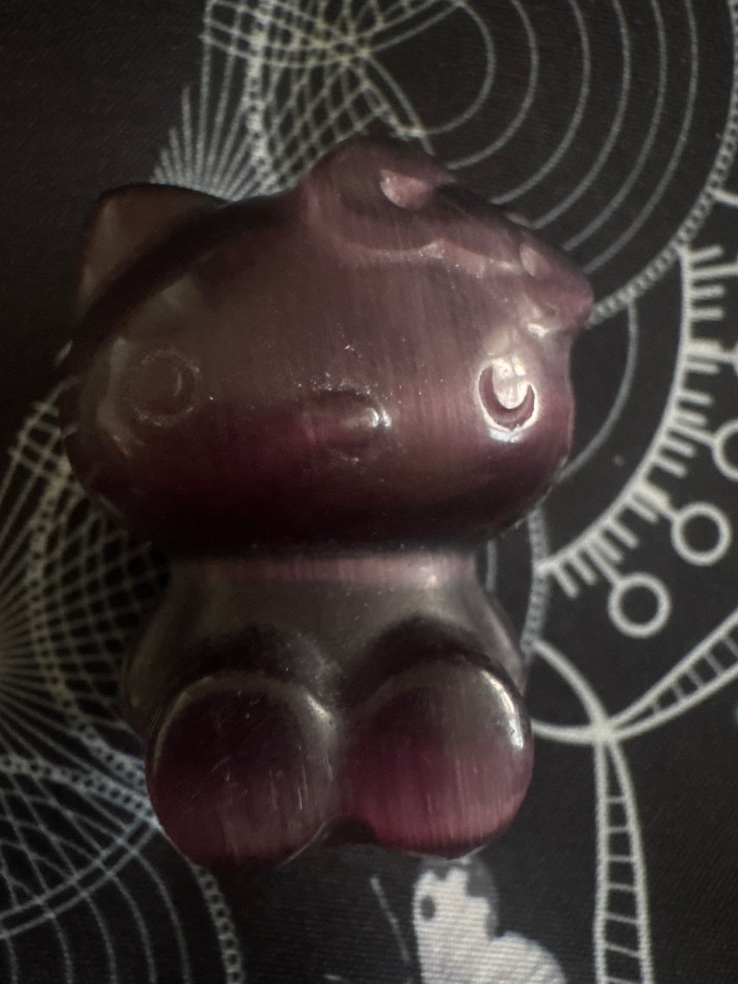 Purple crystal figurine of Hello Kitty on a patterned cloth.