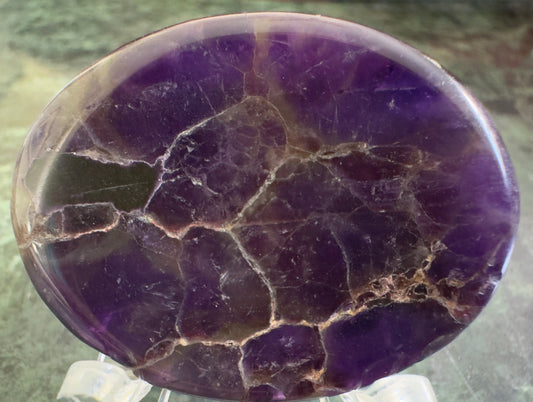 Polished amethyst stone with cracks and purple hues.