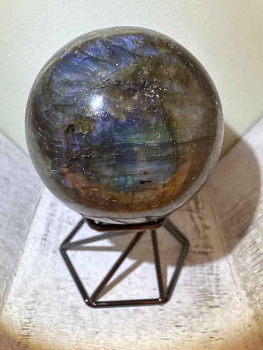 A labradorite sphere on a black metal stand.