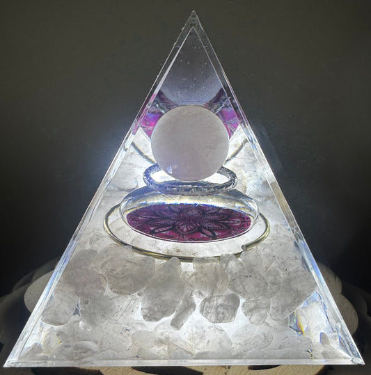 Clear pyramid with white crystals, a sphere, and a mandala design, lit from within.
