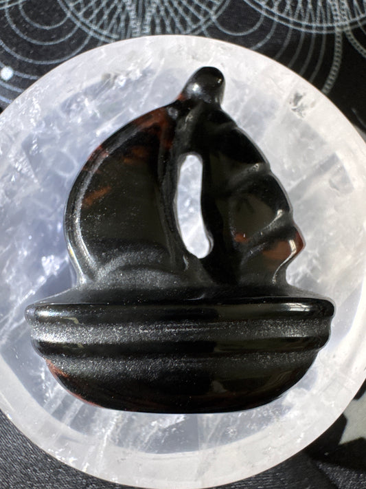 Carved obsidian sailboat on a selenite bowl.