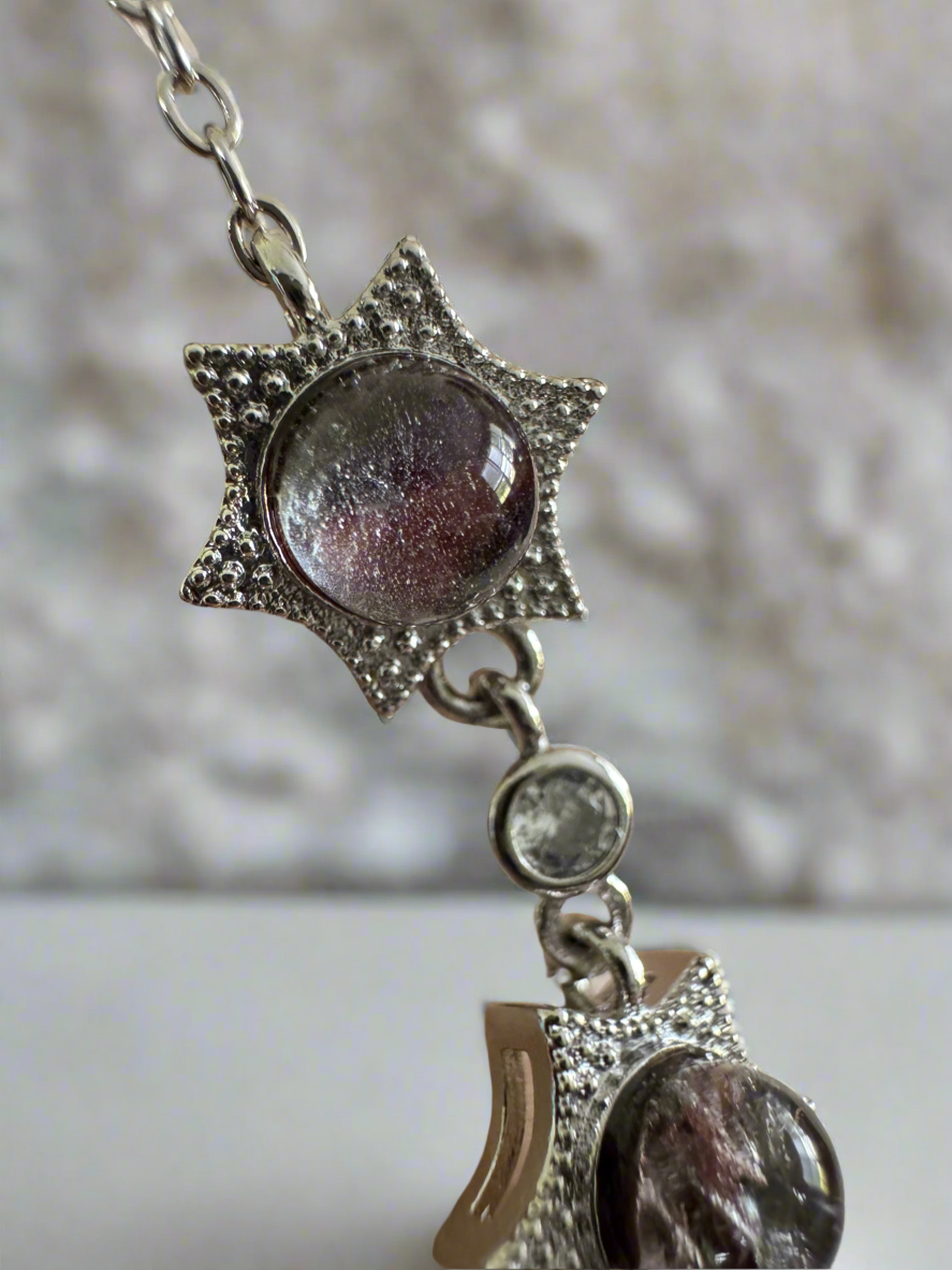 Close-up of a silver necklace featuring star-shaped pendants with clear, iridescent stones.