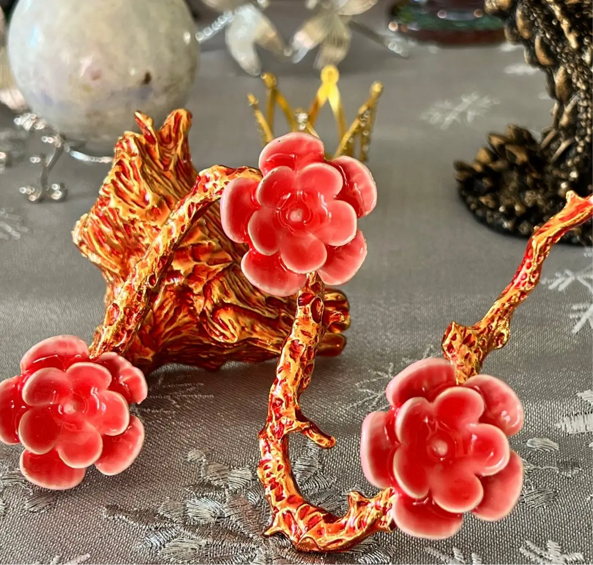 Close-up of red porcelain flower ornaments on gold branches.