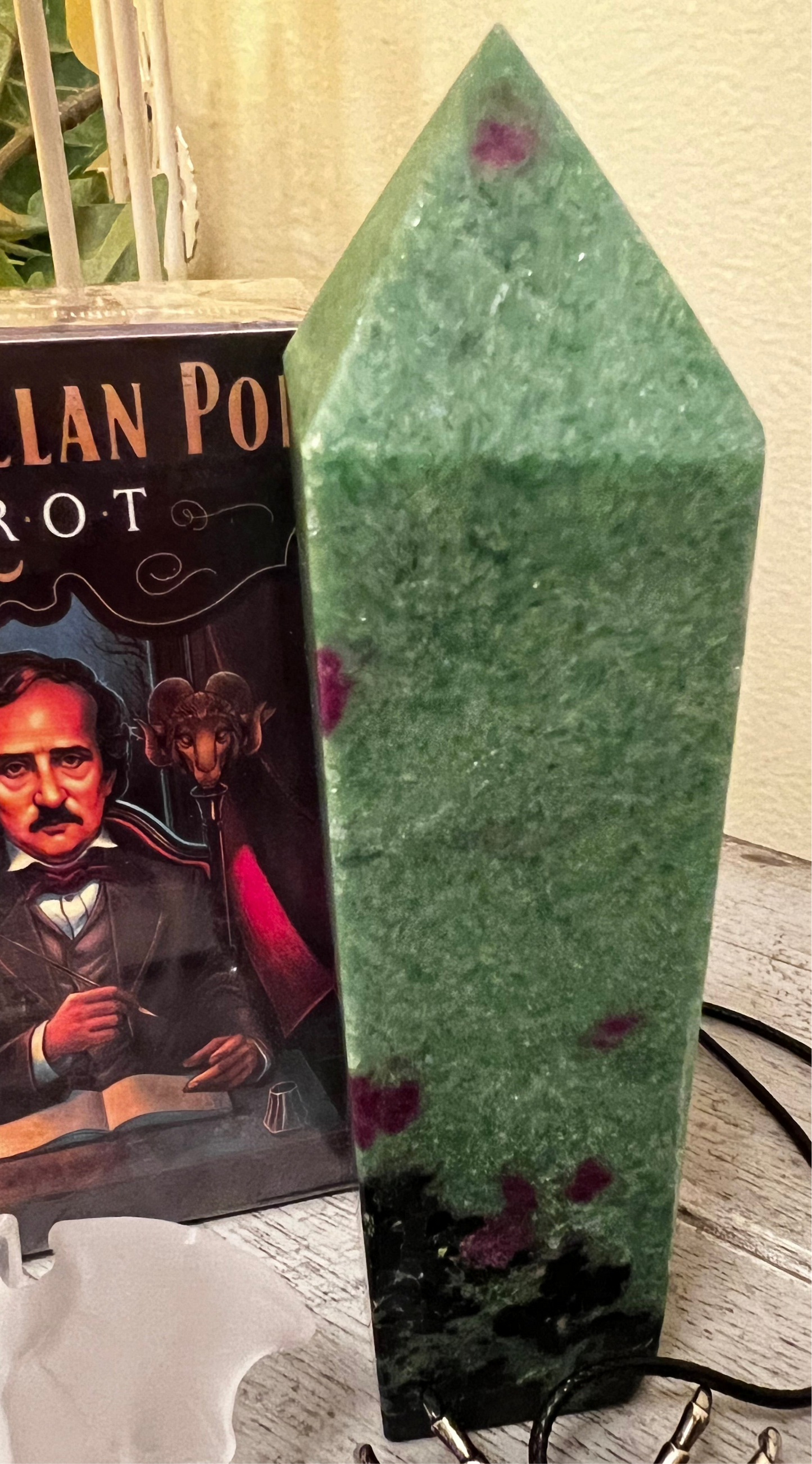 Green and red zoisite crystal point next to an Edgar Allan Poe tarot deck.