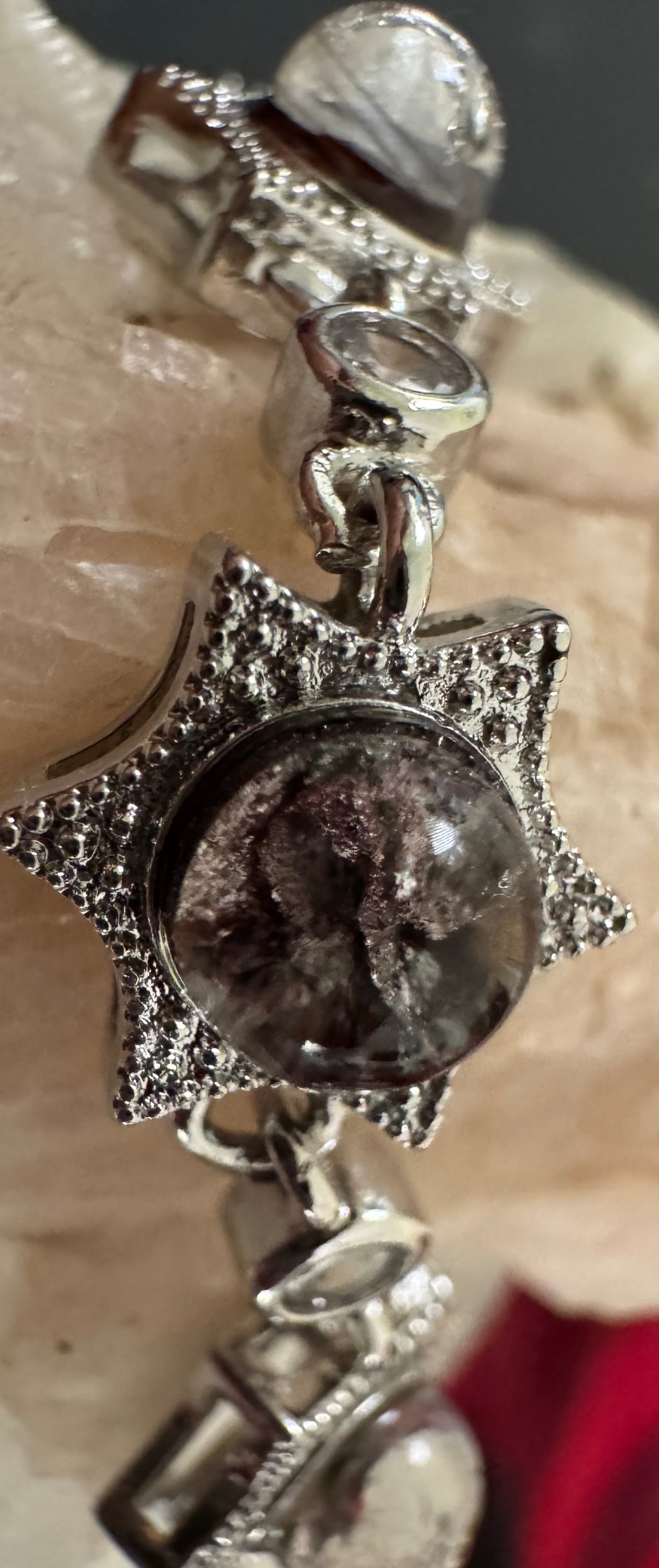 Close-up of a silver pendant with a gray-and-purple-colored glass orb inside.