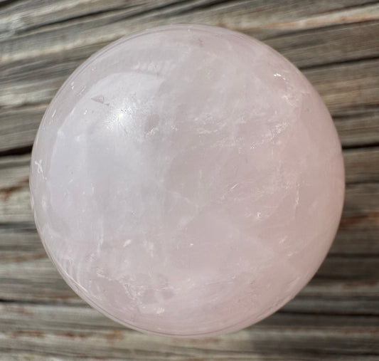 Rose quartz sphere on a wooden surface.