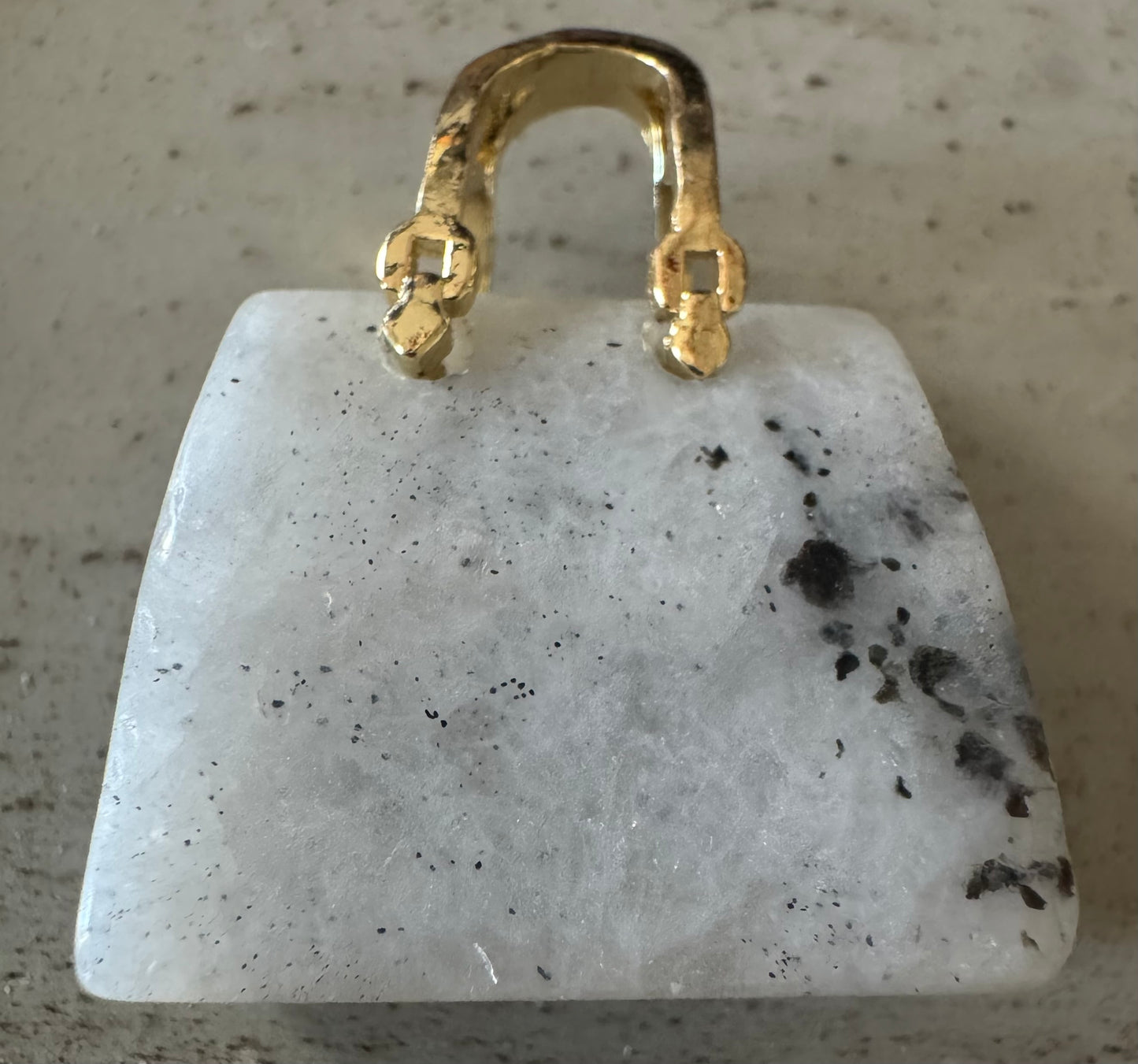 White gemstone pendant with gold bail.