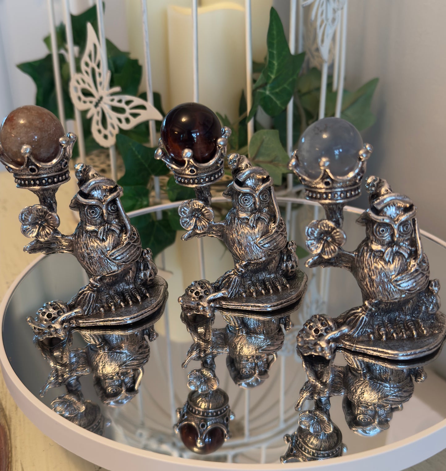three silvery owl sphere display stands on a round mirror stand