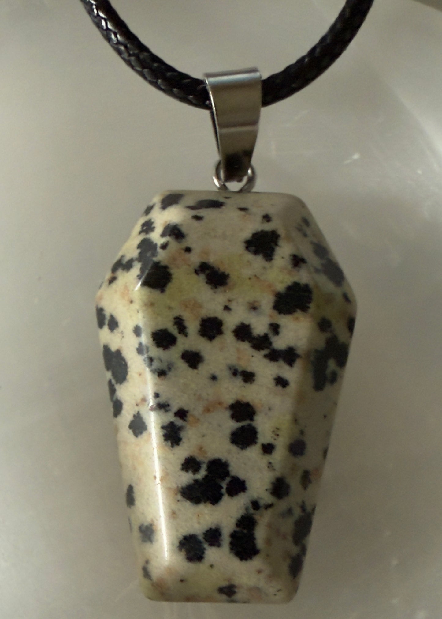 Dalmatian stone pendant on braided black cord necklace.