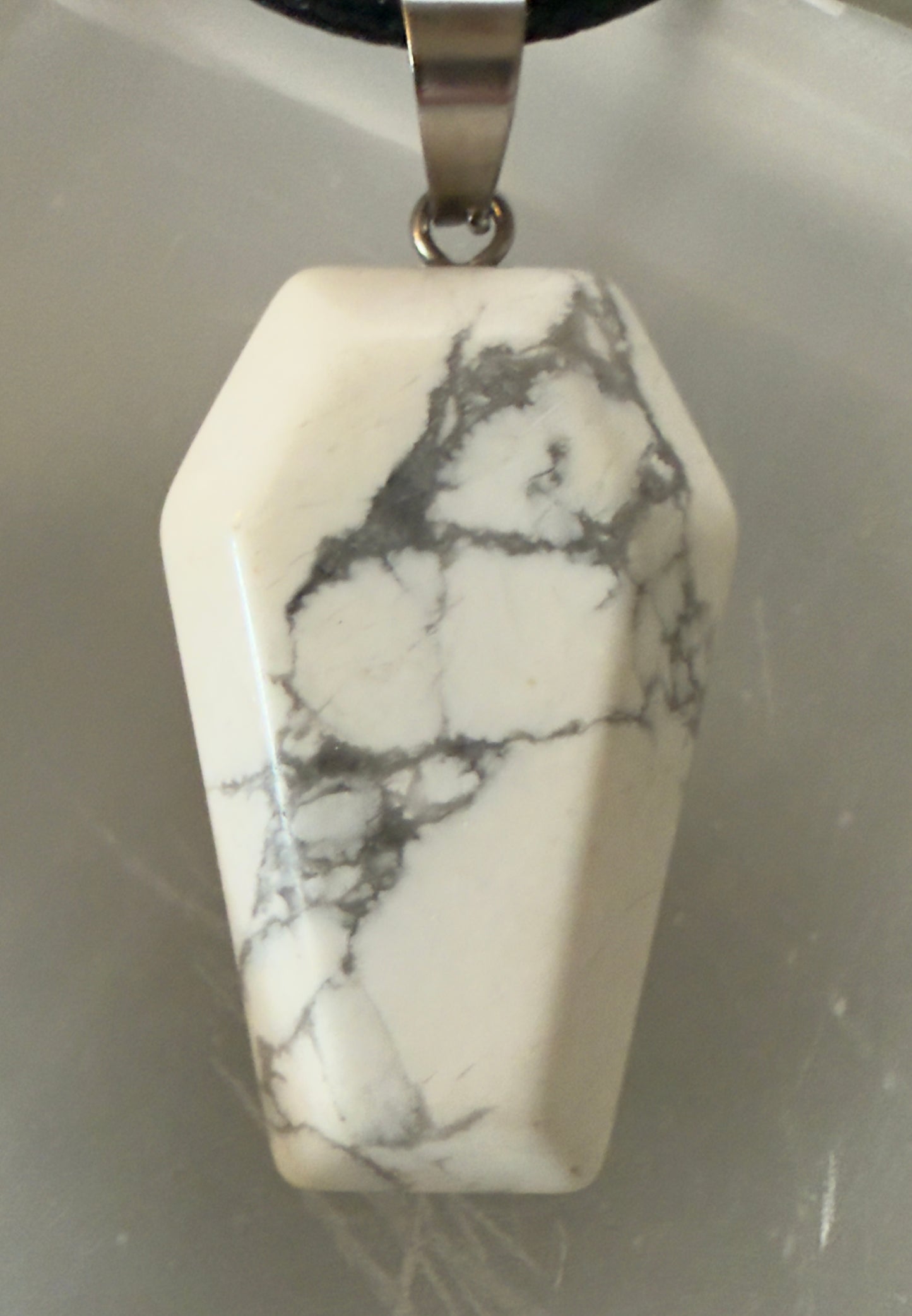 White marble pendant with silver bail and black cord.