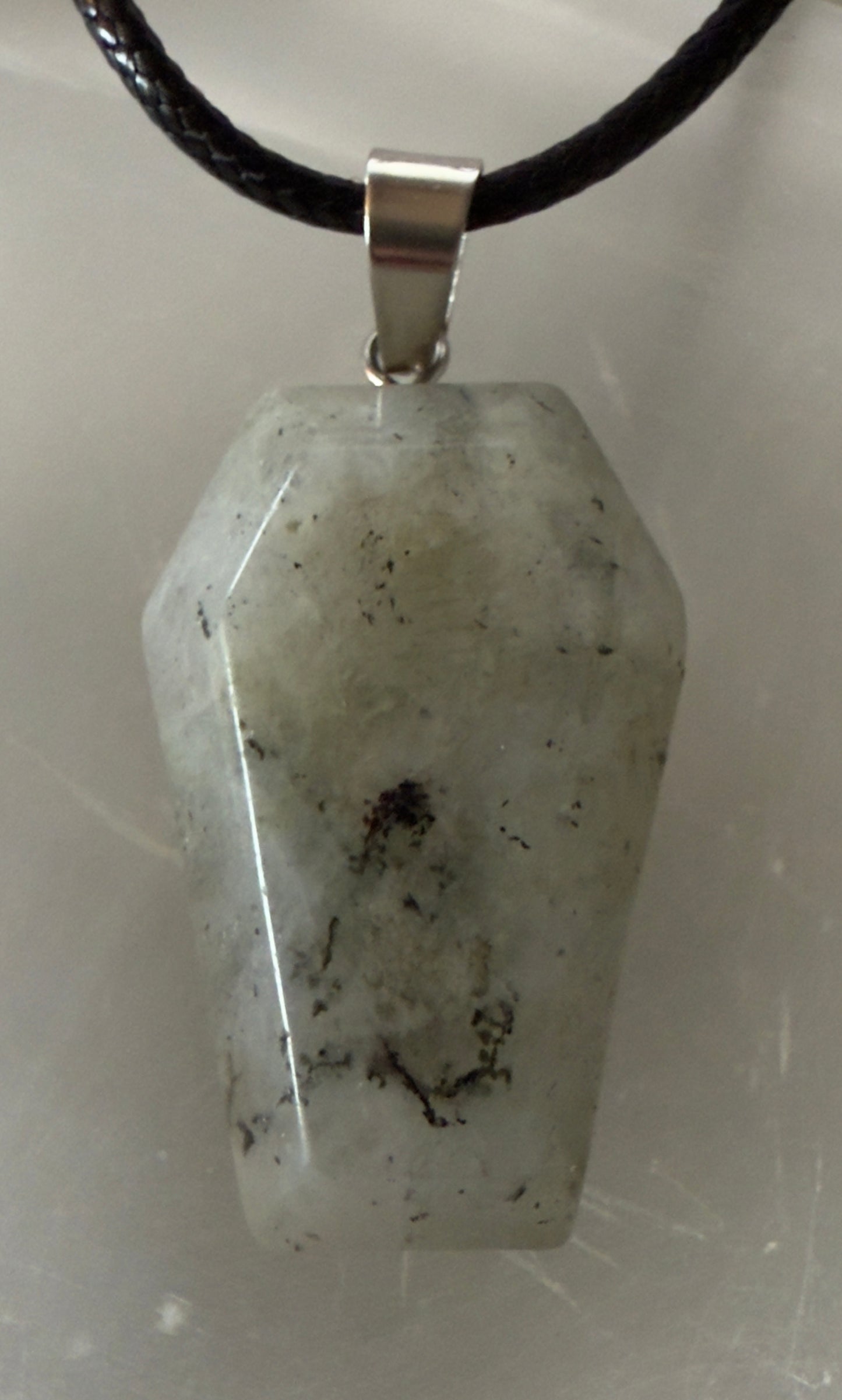 Coffin-shaped moonstone pendant on a black cord.