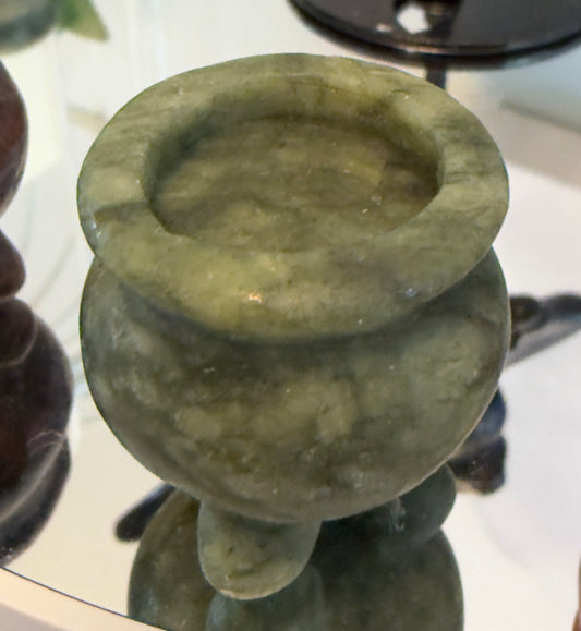 A pale green, carved stone bowl with a lip.