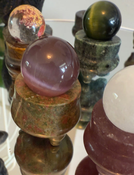 Collection of various crystal balls on stands with a reflective surface.