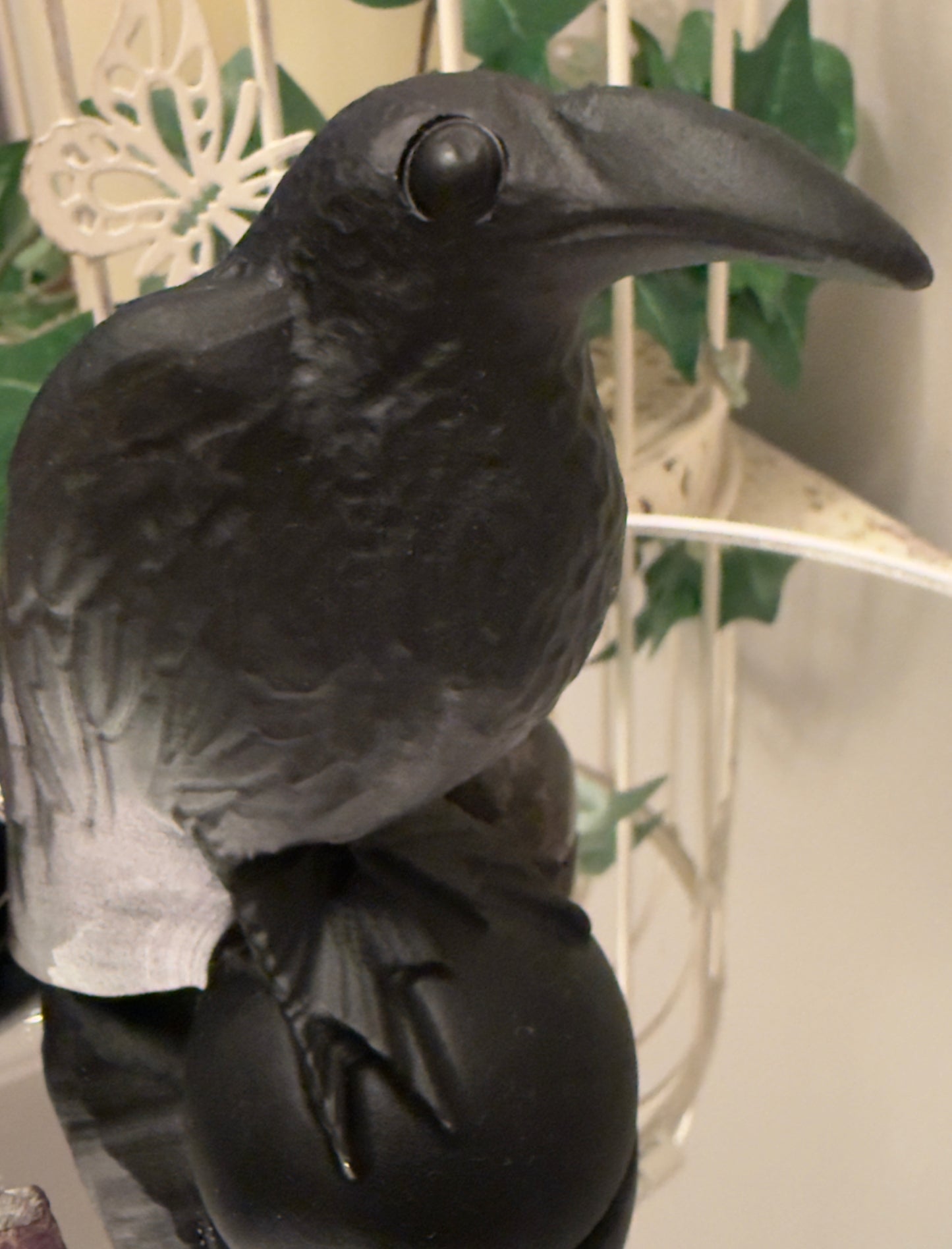 Black crow figure perched on a sphere.
