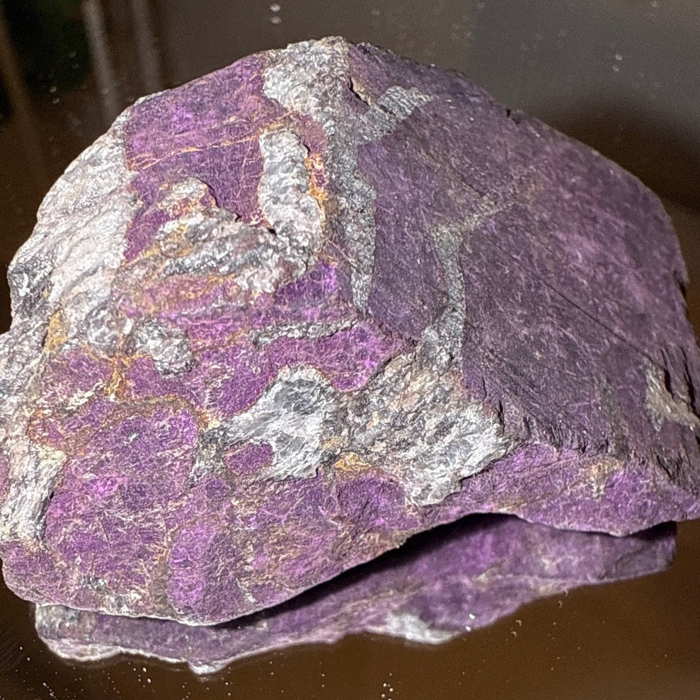 Large purpurite raw specimen on a glass table