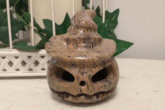 Dendritic Jasper Carved Jack O’Lantern sitting on a white table with greenery behind it