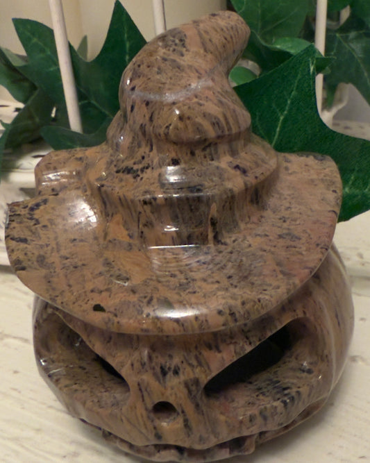Stone carved jack-o'-lantern wearing a witch's hat.
