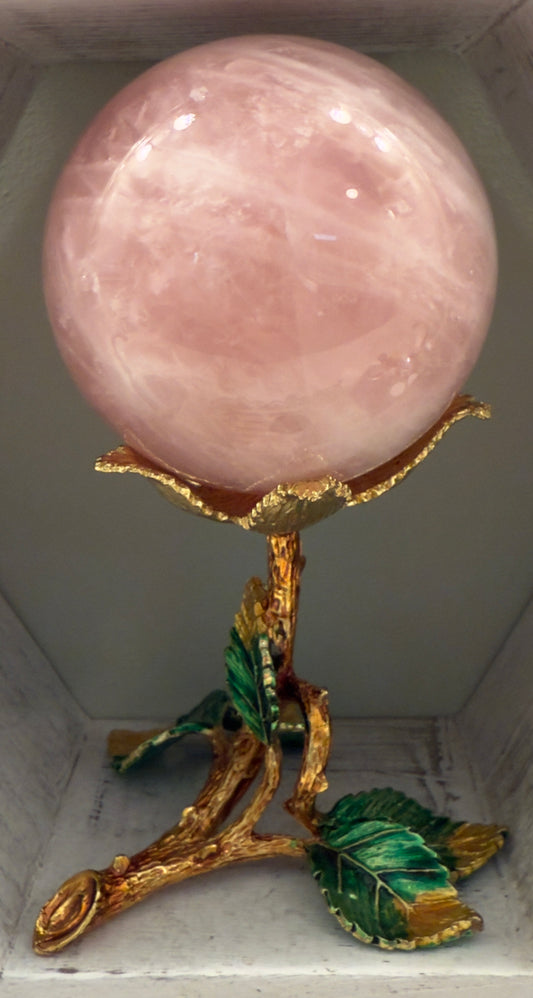 Close up of a Rose Quartz Sphere in a gold toned stand
