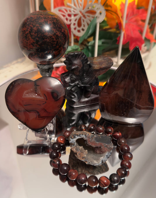 Mahogany obsidian crystal set featuring a sphere, heart, pyramid, bracelet, geode, and dragon carving, with earthy red and black tones for grounding and protection