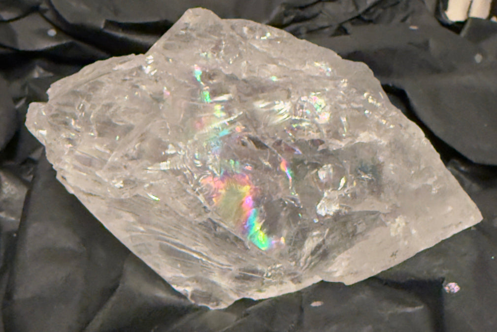 Clear crystal rock with iridescent properties on a black background