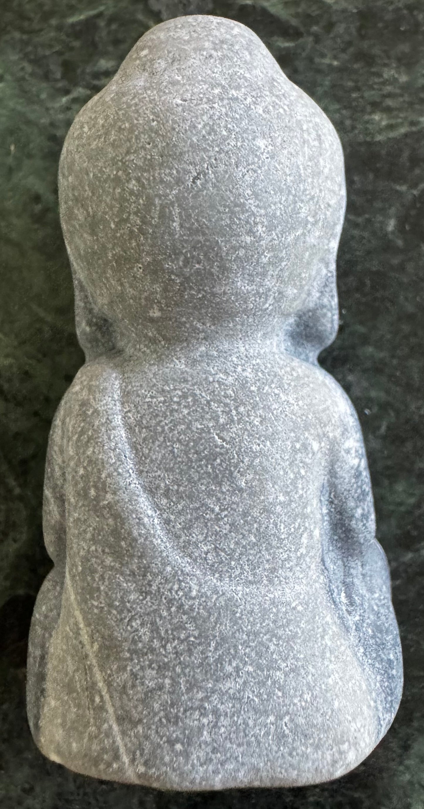 Back view of a gray stone Buddha statue.