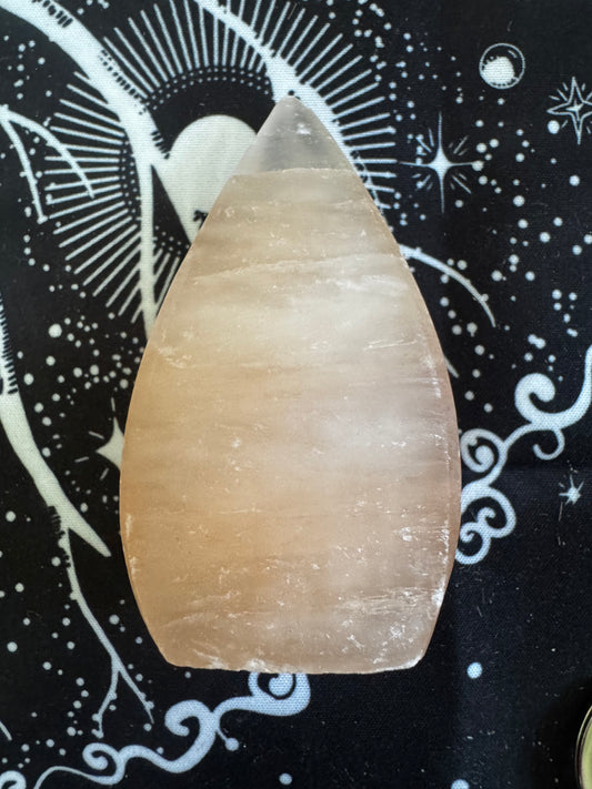 Pink Himalayan salt lamp in a drop shape on a black and white patterned cloth.