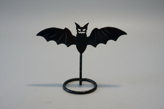 Black bat-shaped object on a stand against a neutral background