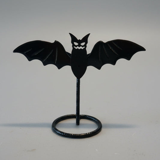 Black bat-shaped object on a stand against a neutral background