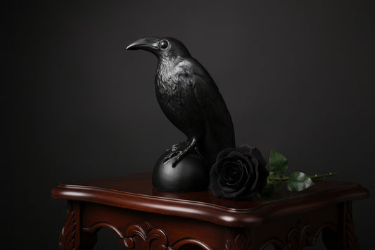 Black crow figurine on a wooden surface with a neutral background