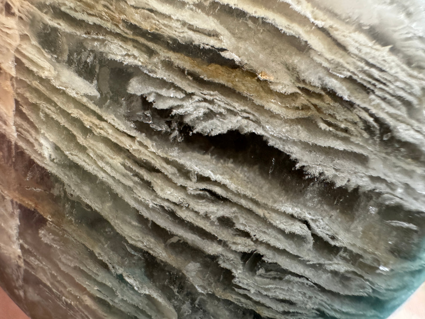 Layered translucent mineral with off-white and gray hues.