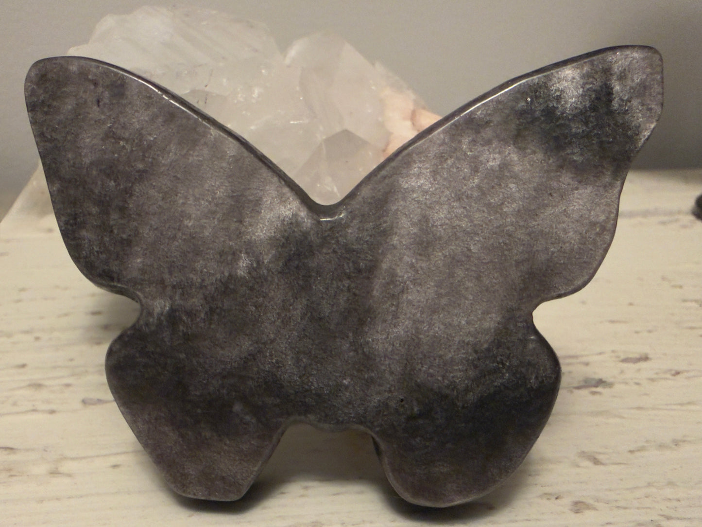 Golden Sheen Obsidian crystal carved butterfly leaning on a white rock.