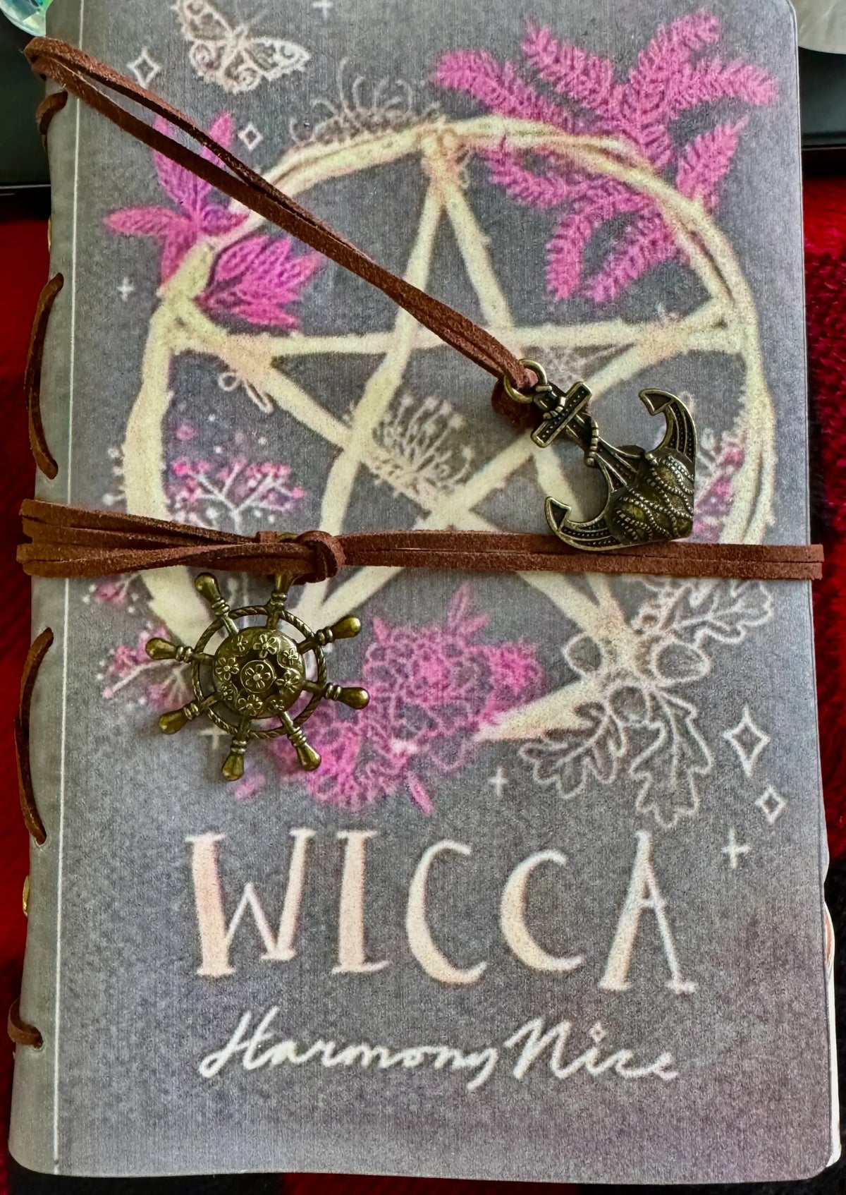 Closed "Wicca" journal with pentacle, plants, and anchor and ship wheel charms.