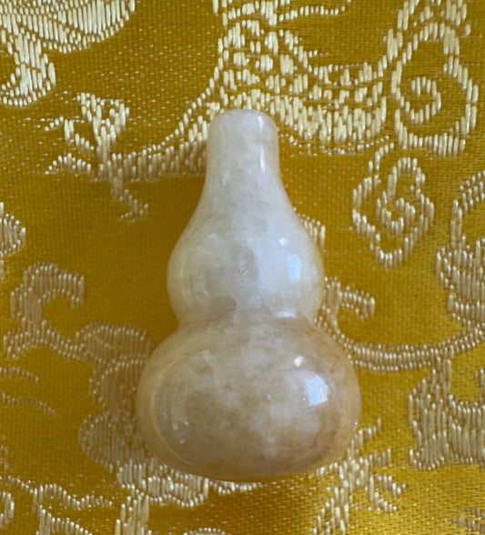 Light yellow jade gourd on patterned yellow fabric.