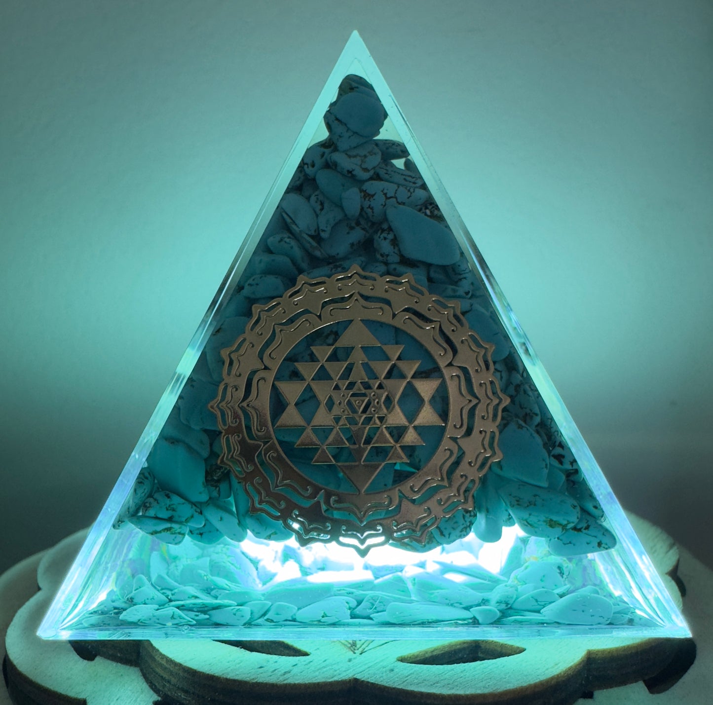 Illuminated pyramid with turquoise stones and golden geometric design.