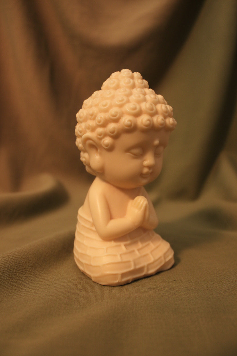 Baby buddha in praying pose with soft green and brown fabric