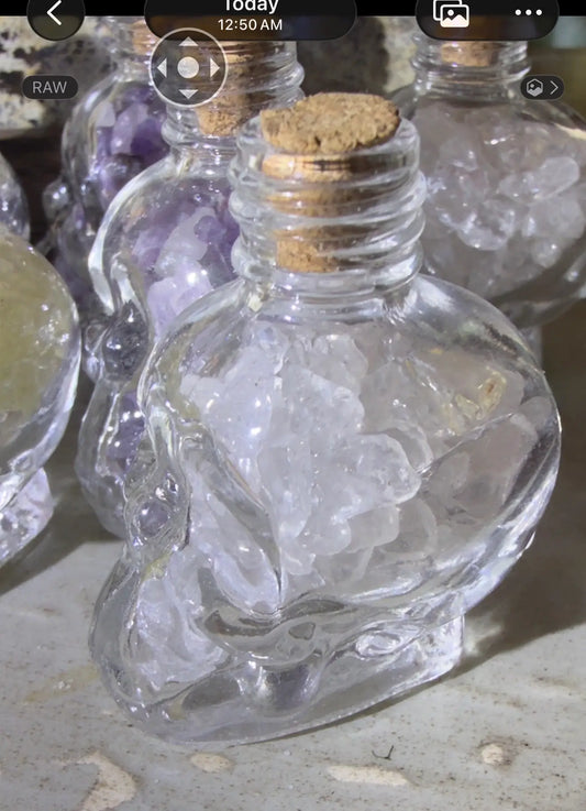 Clear quartz crystal chips in a skull shaped bottle with a cork