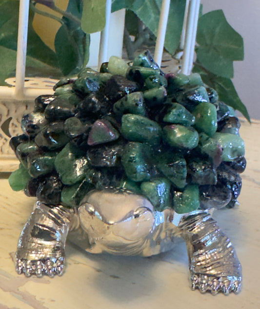Close-up of a decorative silver turtle covered in green and black stones.