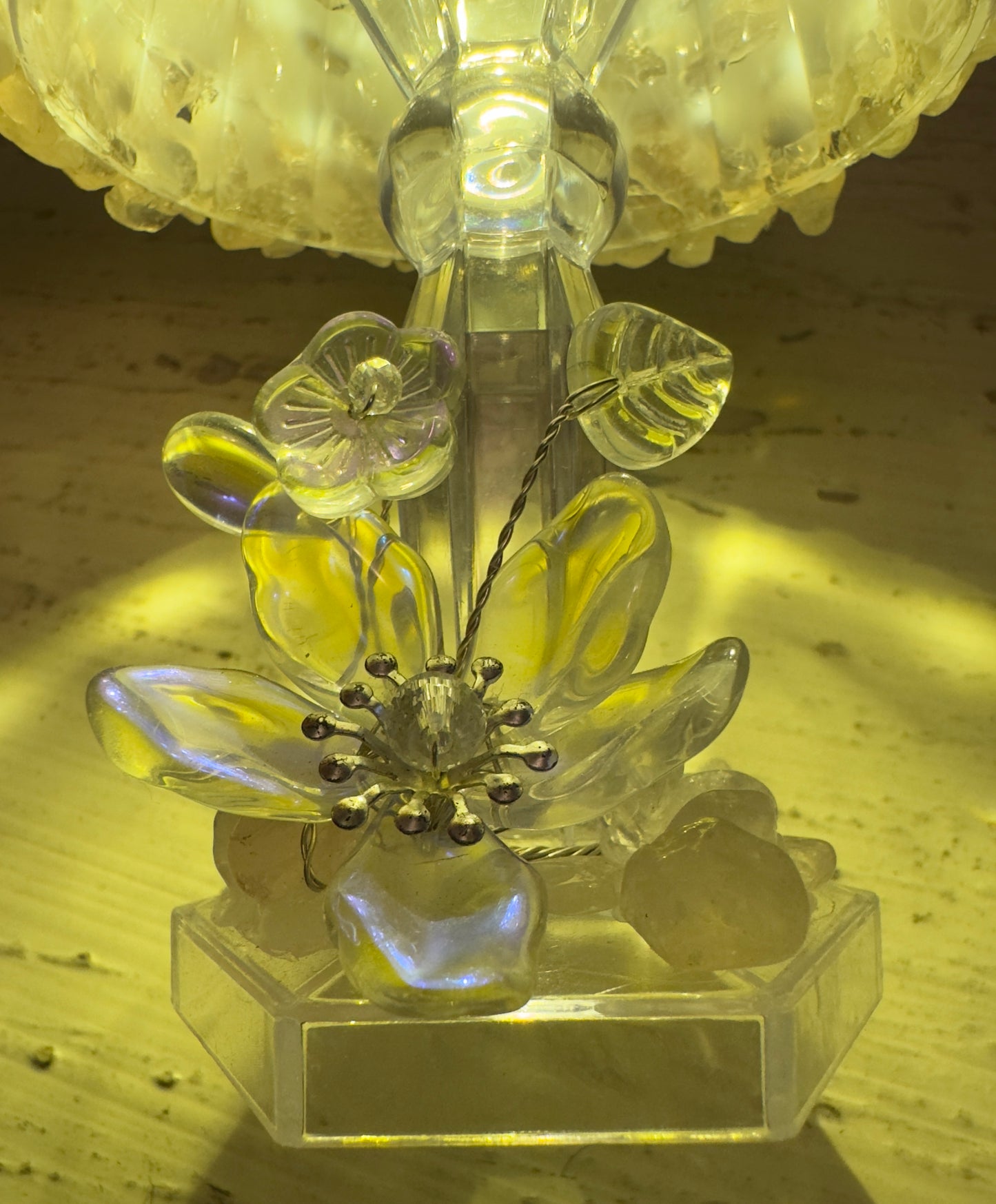 Close-up of a clear plastic flower sculpture with a light shining through it.
