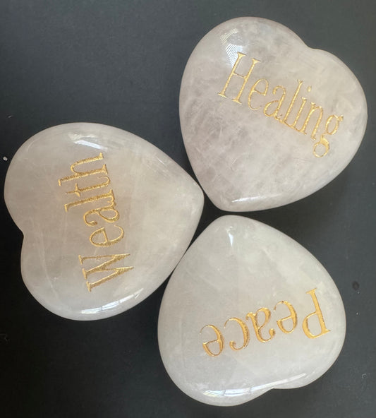 Three white heart-shaped stones with gold lettering.