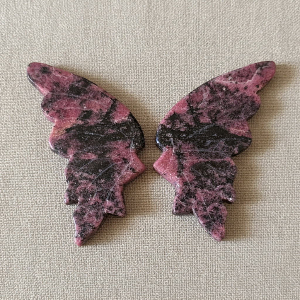 a set of pink and black rhodonite crystal carved wings