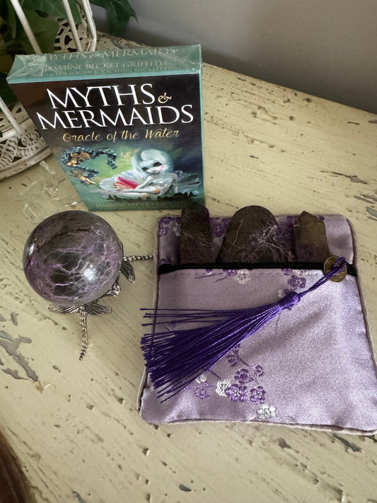 Oracle deck with purple crystal ball and tassel pouch on weathered wooden surface.