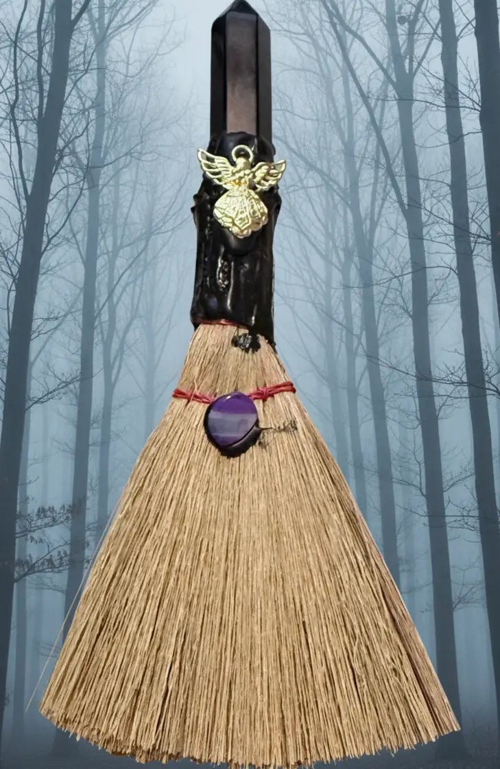 Small besom natural bristles gold tone angel charm black obsidian finial background muted foggy forest