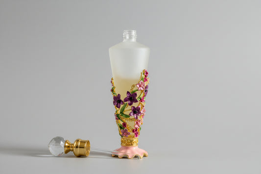 close up of frosted glass fragrance bottle flowers, lid with glass rod applicator