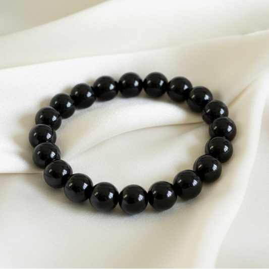 close up of black onyx 8mm bead bracelet on an off white color fabric