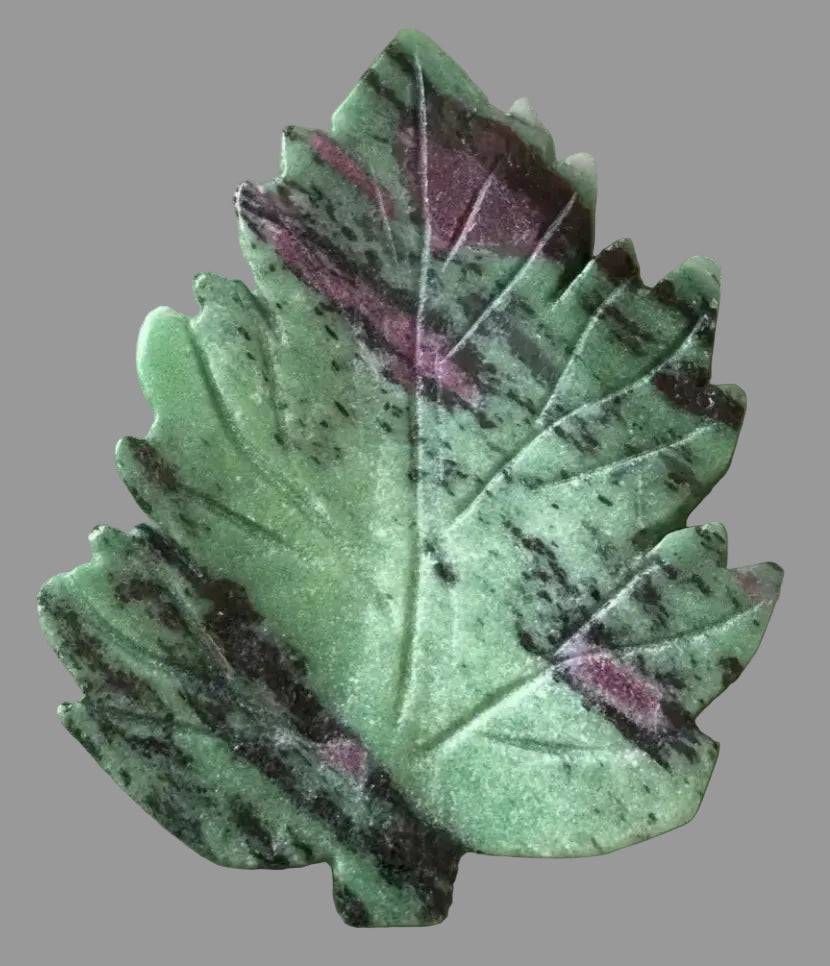 close up leaf carved from ruby zoisite crystal. bright green, black and pink throughout